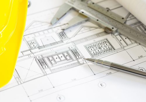 construction-plans-with-yellow-helmet-drawing-tools-bluep-scaled.jpg